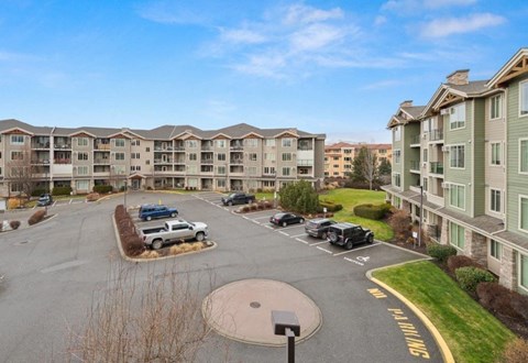 A parking lot in front of apartment buildings with cars parked.