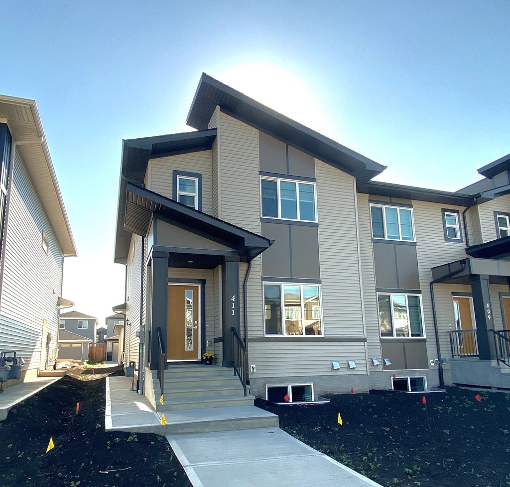A modern house with a front yard and a clear sky.