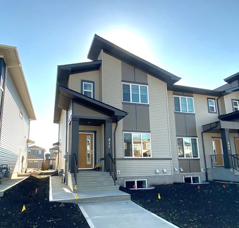 A modern house with a front yard and a clear sky.