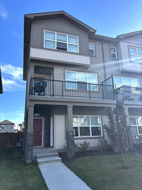 A two-story residential building with a red door and a balcony.