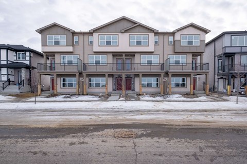 A row of multi-story apartment buildings with balconies and doors.