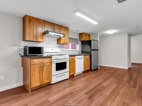 A kitchen with wooden cabinets and a black fridge.