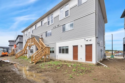 A grey building with a wooden staircase leading to the entrance.