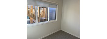 A room with a window showing a view of a wooden structure.