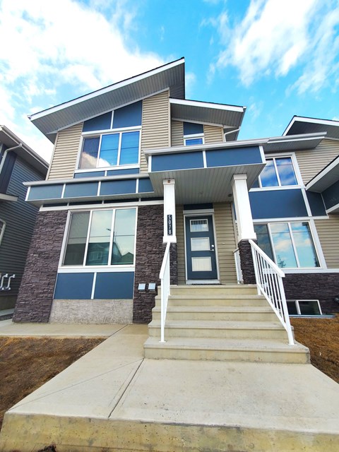 A modern house with a front porch and stairs leading to the entrance.