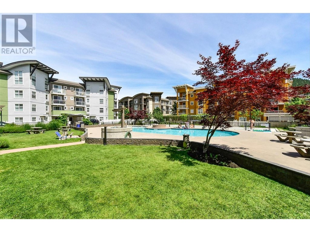 A large grassy area with a pool and apartment buildings in the background.