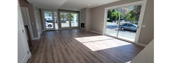 A room with wooden floors and a large window showing a parking lot outside.