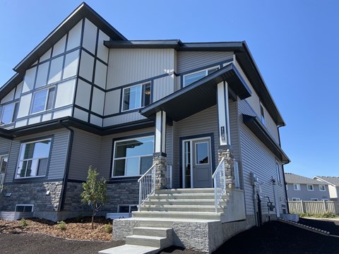 A modern house with a grey and white exterior and a balcony on the upper floor.