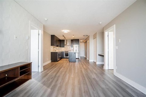 an empty living room and kitchen with wood floors