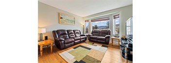 A living room with brown leather couches and a landscape painting on the wall.