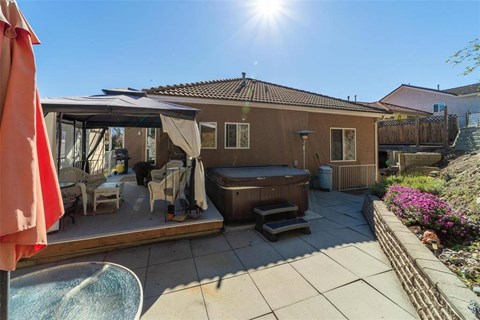 A sunny day at a patio with a hot tub and chairs.