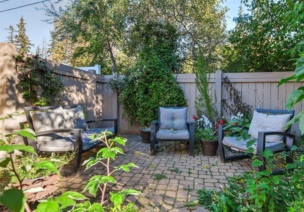 A backyard with a brick patio and two chairs.