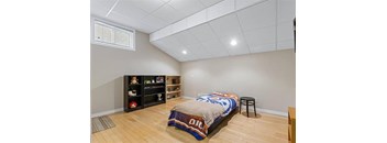 A bedroom with a bed, a chair, and a bookshelf.
