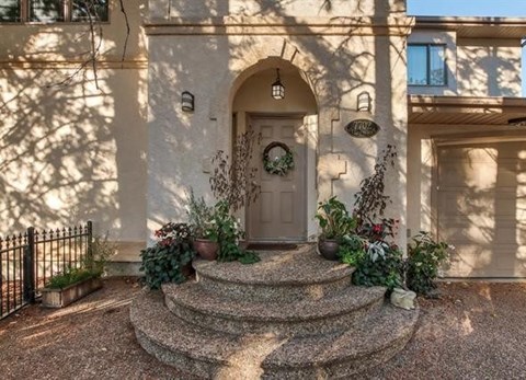 A house entrance with a wreath on the door and plants on the steps.