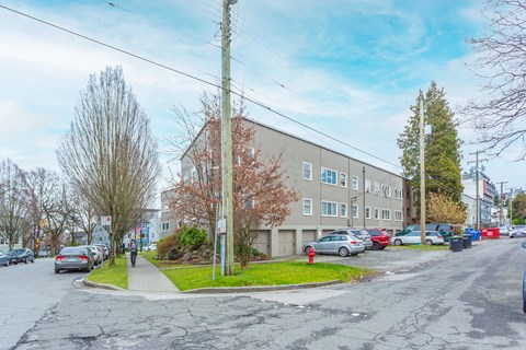 A grey building with a parking lot in front of it.