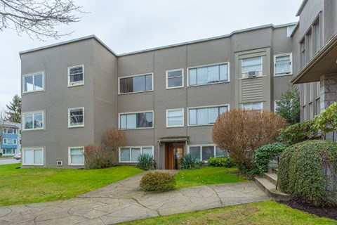 A grey building with a brown door and windows.