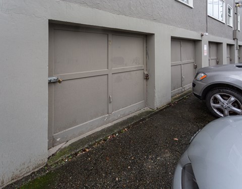 A grey car is parked in front of a grey garage door.