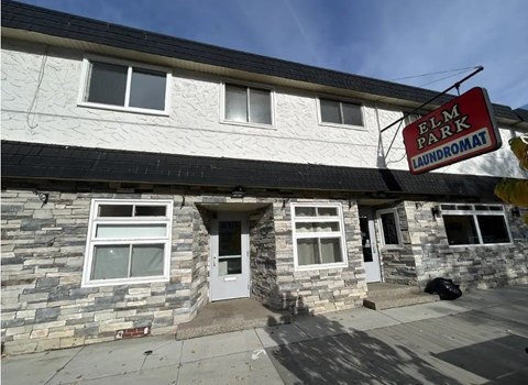 A laundromat named Elm Park is located in a building with a stone facade.