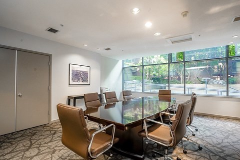 A conference room with a table and chairs and a painting on the wall.