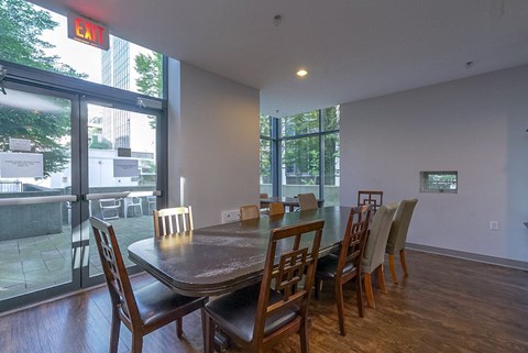 A dining room with a table and chairs and a red exit sign above it.