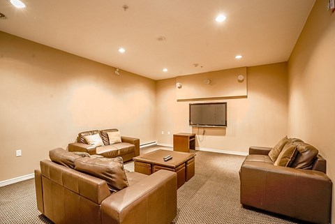 A living room with a brown leather couch and a television mounted on the wall.