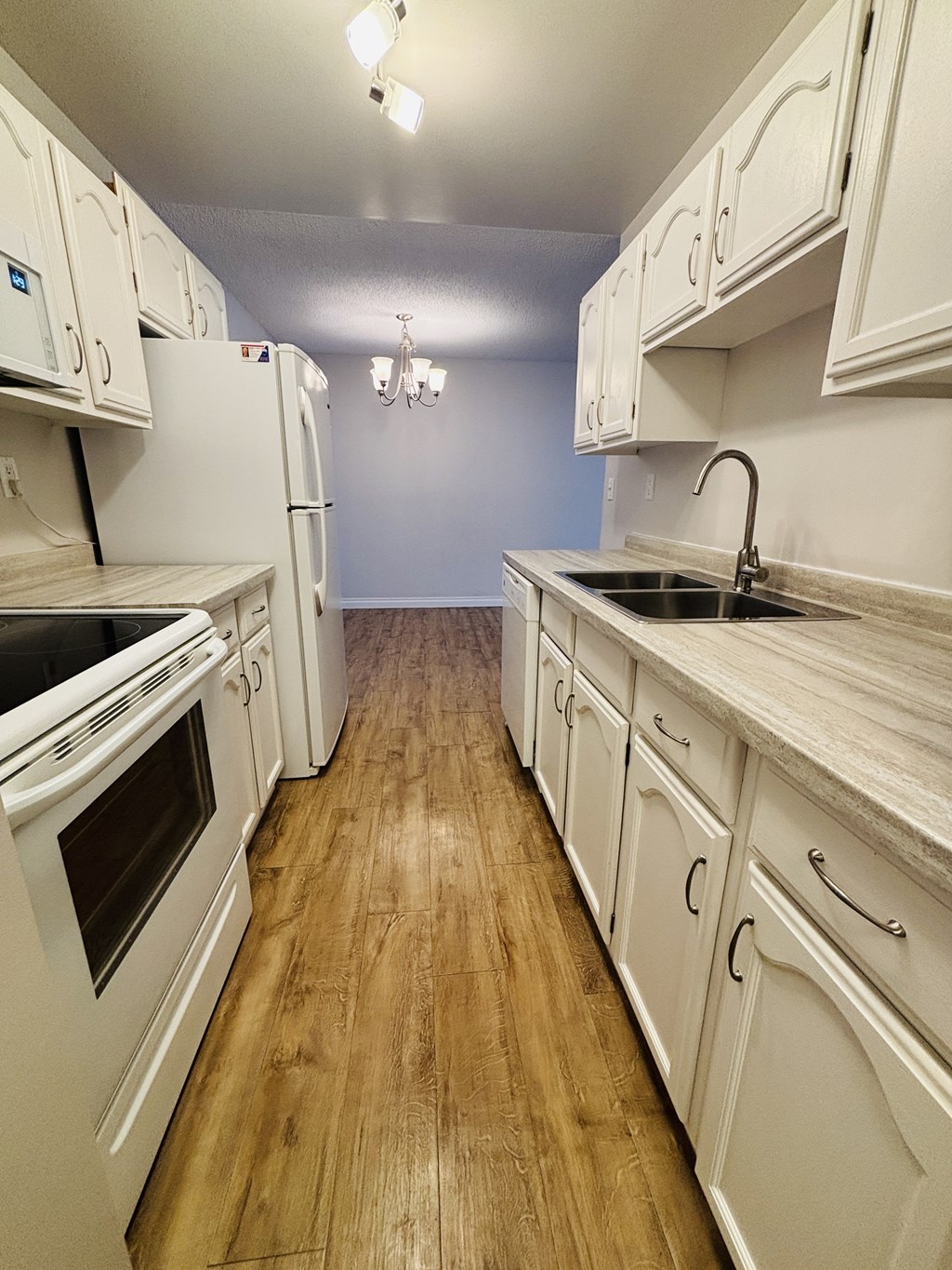 A kitchen with white cabinets and appliances.