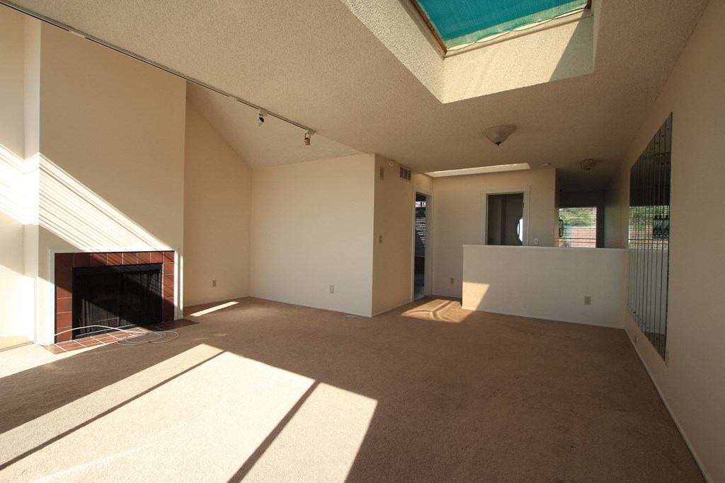 a large living room with a fireplace and a large skylight