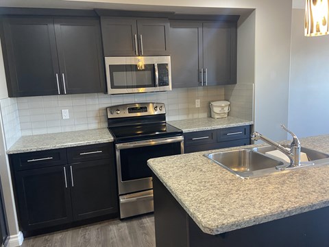 A kitchen with black cabinets and a granite countertop.