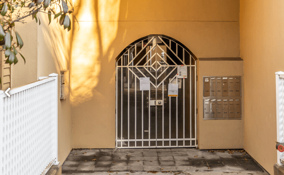 a gate in front of a building with a yellow wall
