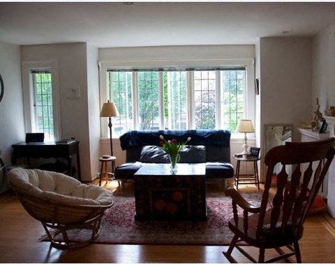 A living room with a blue couch and a wooden rocking chair.