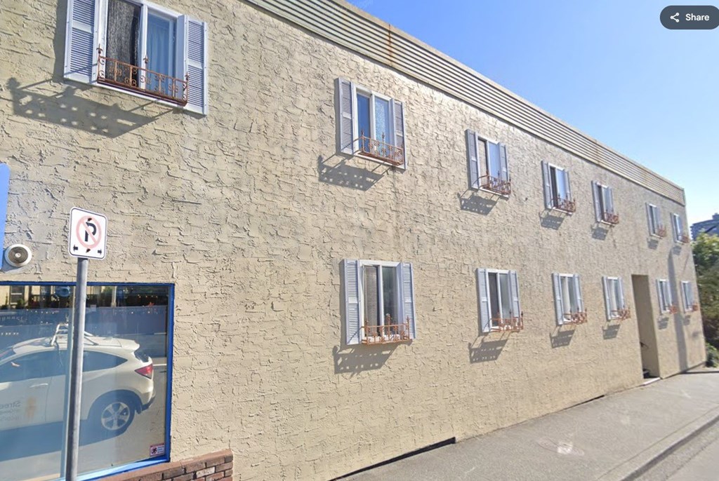 A building with a car advertisement on a pole in front of it.