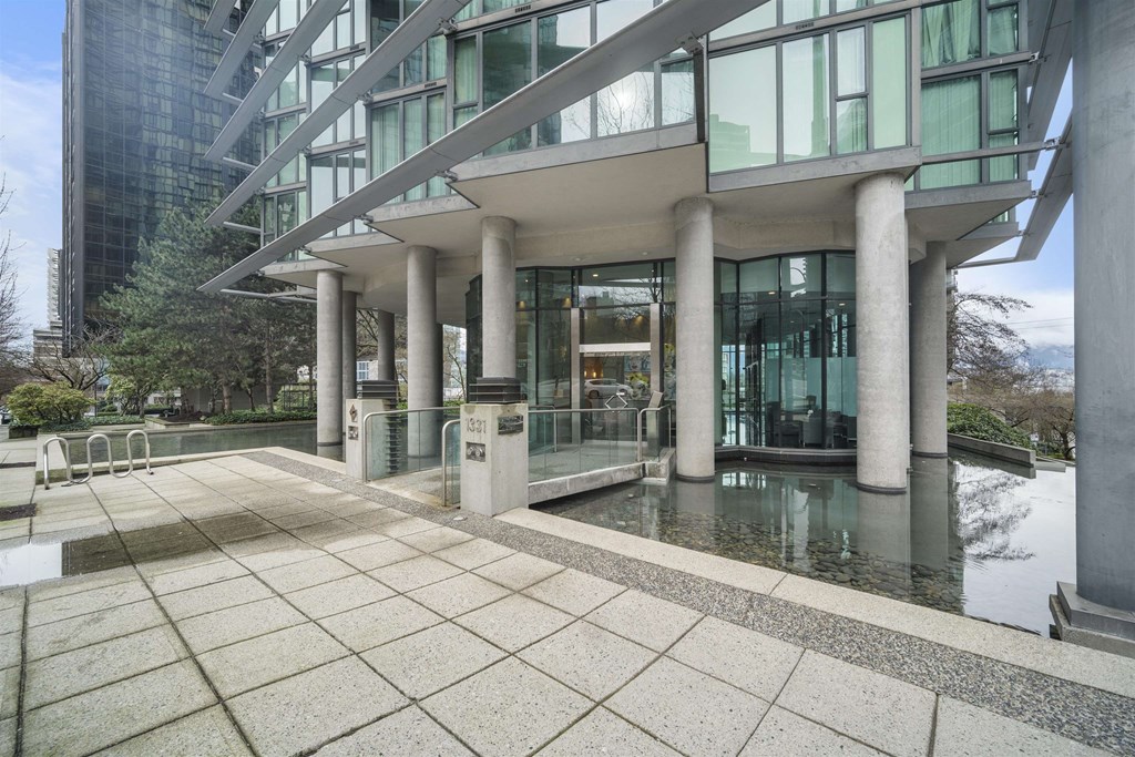 A modern building with a glass facade and a water feature in front.
