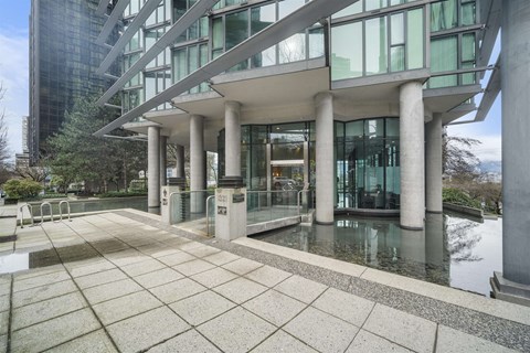 A modern building with a glass facade and a water feature in front.