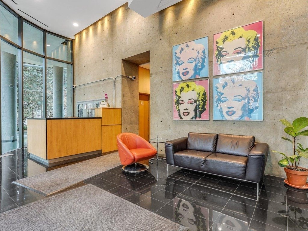 A reception area with a chair, couch, and a potted plant.