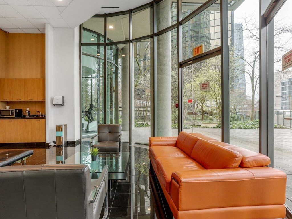 A modern office lobby with a glass wall and a bright orange couch.