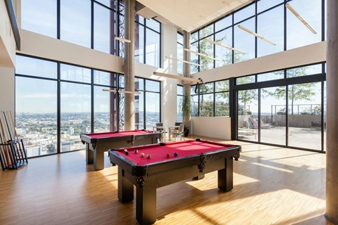 A room with a pool table and a view of the city.