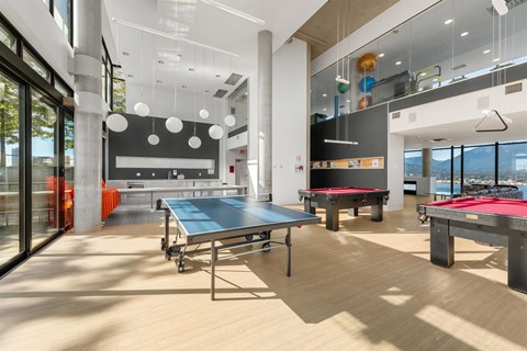 A ping pong table is in the middle of a room with a pool table and a foosball table.