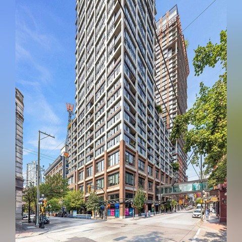 A tall building with many windows is in the middle of a city street.