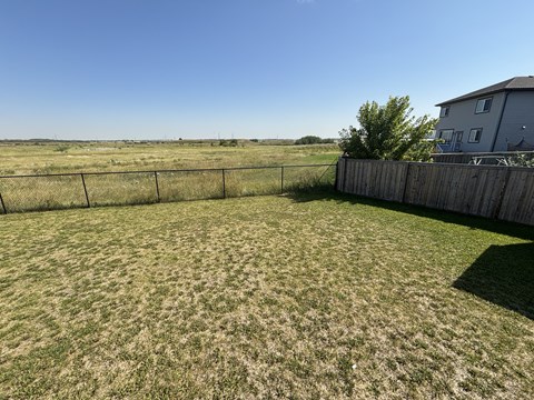A backyard with a fence and a house in the background.