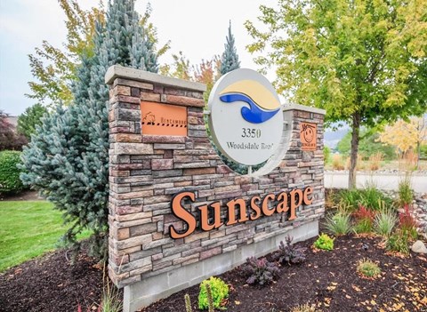 A sign for Sunscape with a blue wave logo and a maple tree in the background.