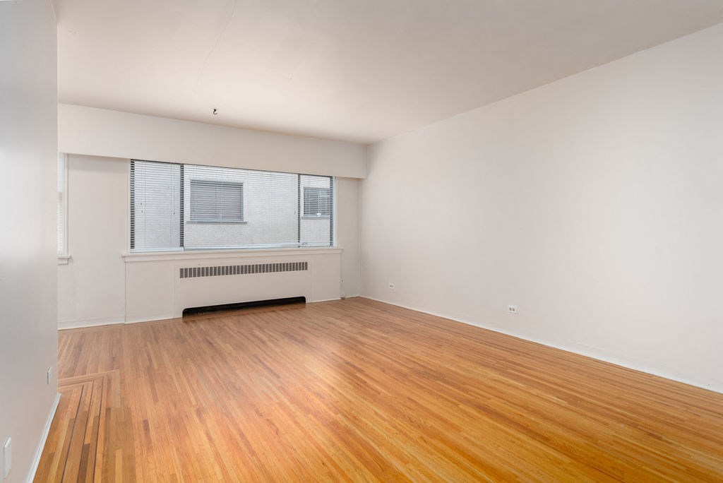 a bedroom with hardwood floors and white walls