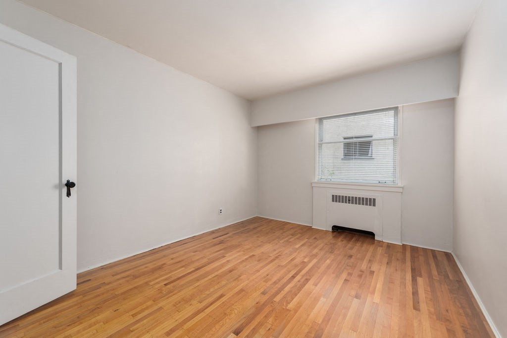a bedroom with hardwood floors and white walls