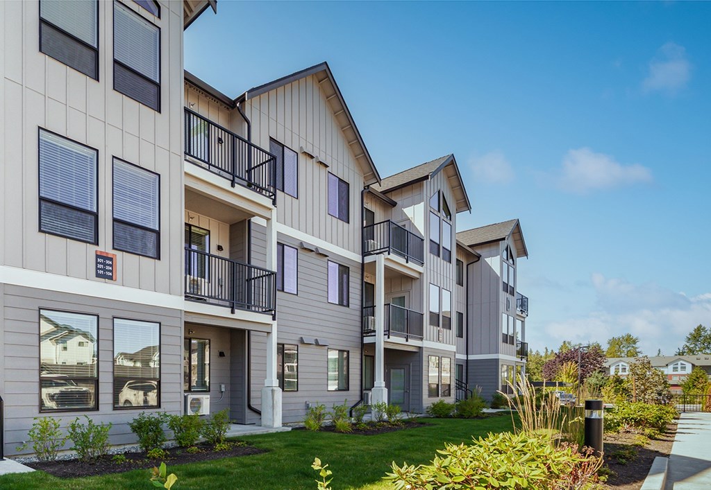 A row of modern townhouses with balconies and landscaped gardens.