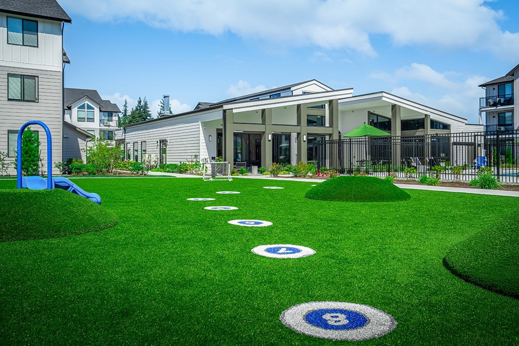 A playground with a slide and a building in the background.