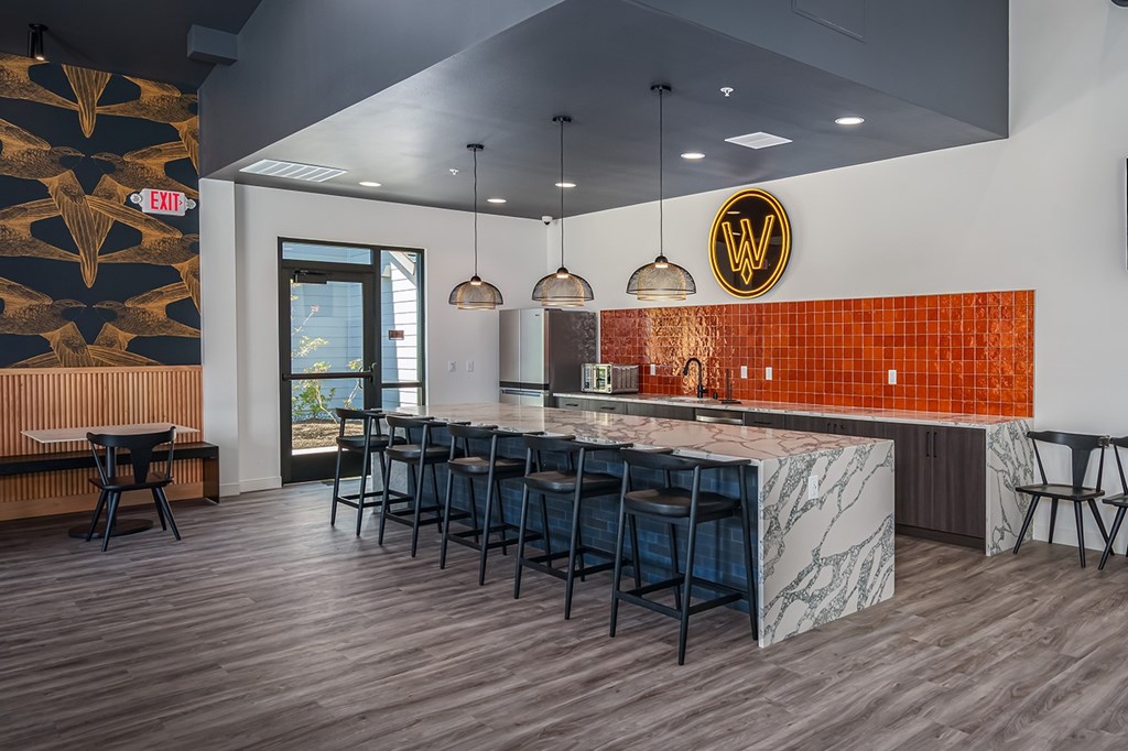 A bar with a white counter and black stools.