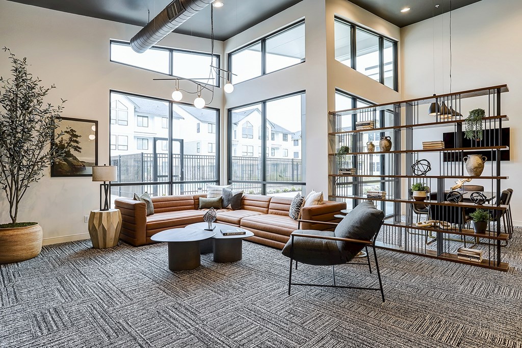 A living room with a grey carpet and a large window.
