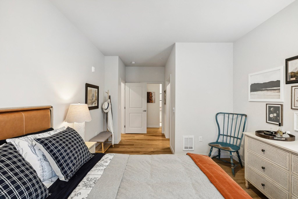 a bedroom with a bed and a dresser and a door to a hallway