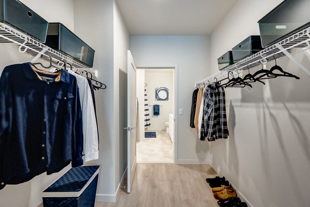 a walk in closet with clothes hanging on a rack and a door to a bathroom