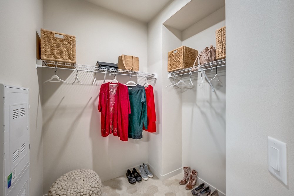 a walk in closet with clothes hanging on the wall and shoes on the floor