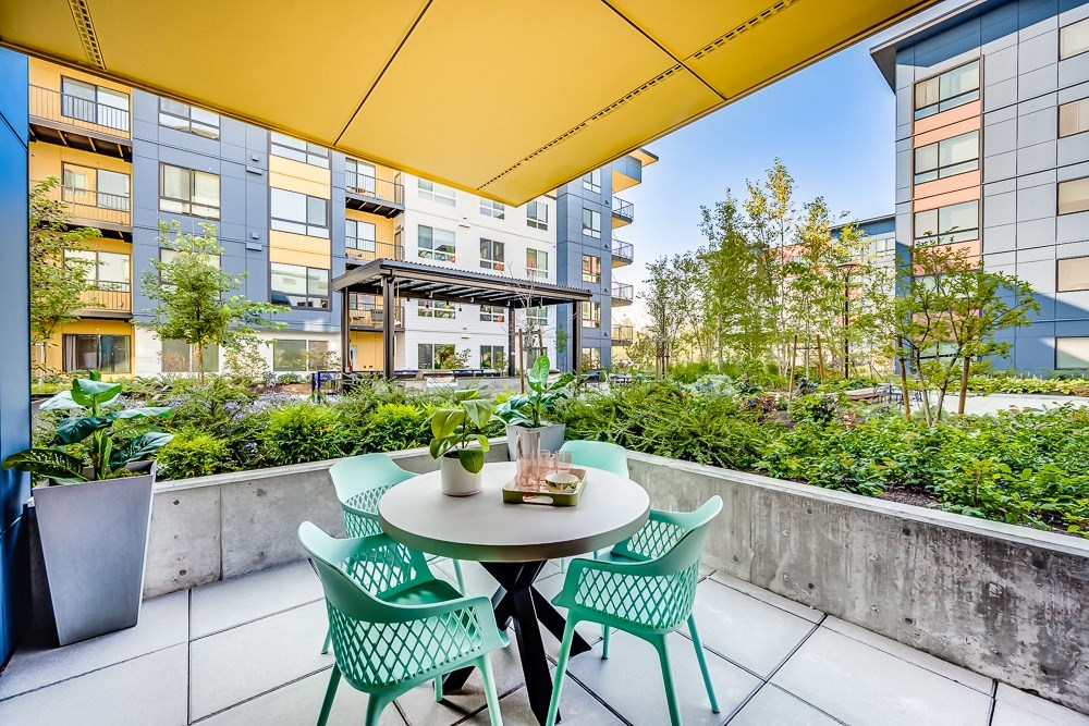 a patio with green chairs and a table and a yellow canopy